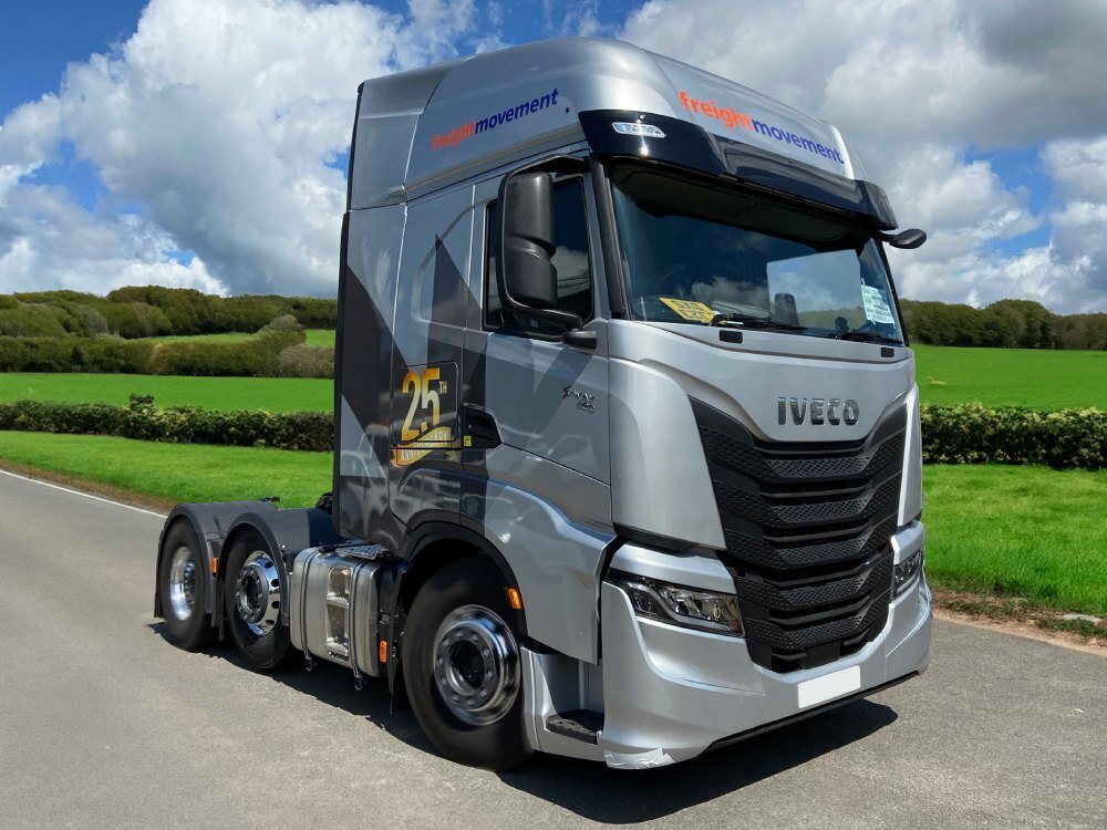 Vehicle wrap and graphics on an Iveco lorry driving along a road.