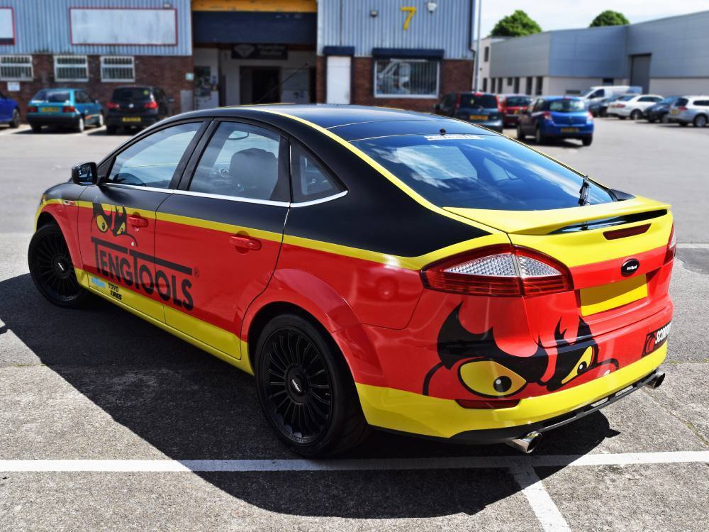 Rear of Ford Mondeo company car with bold red and yellow commercial wrap.