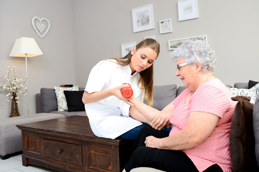 Young physiotherapist with elderly patient at home