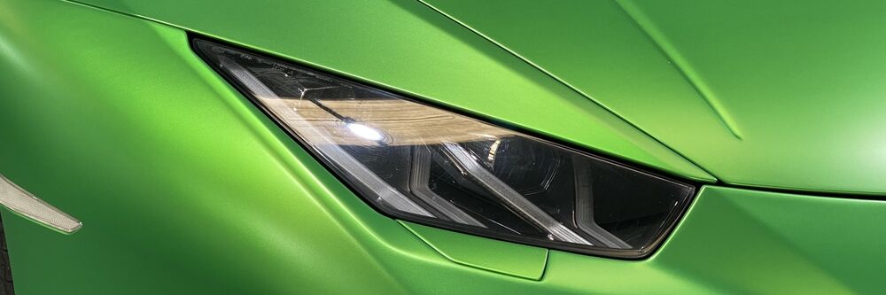 Close up of green vehicle wrap and front headlight on sports car