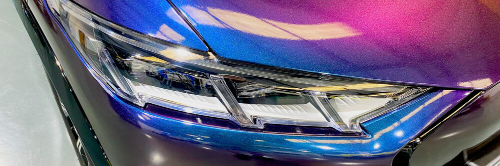Close up of blue vehicle wrap and front headlight on sports car