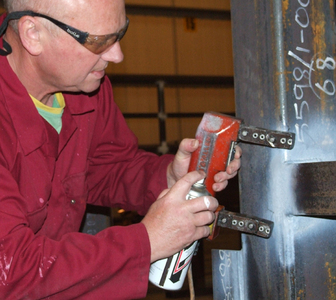 Carrying out NDT MPI on a carbon steel weld on a offshore fabrication using a Electromagnetic Yoke, White background paint and black magnetic search media   .