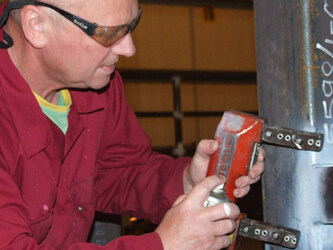 Carrying out NDT MPI on a carbon steel weld on a offshore fabrication using a Electromagnetic Yoke, White background paint and black magnetic search media   .